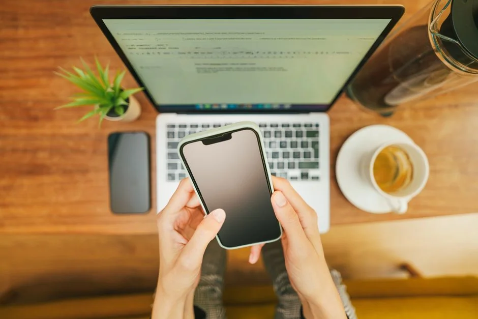 Close-up of a person trading stocks using a smartphone and a tablet.